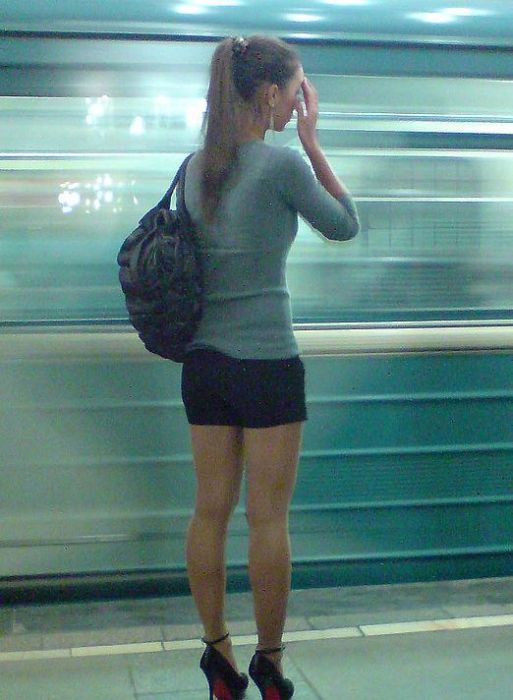 Блондинка в колготках и короткой юбке стоит на остановке а тип снимает на камеру ее ножки